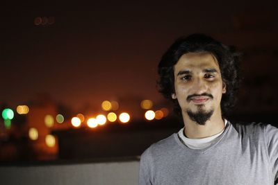 Portrait of man against illuminated lights at night