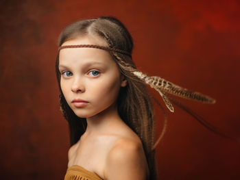 Close-up portrait of girl against red background