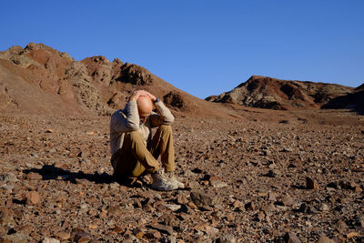 Lonely abandoned senior man sitting in the desert 