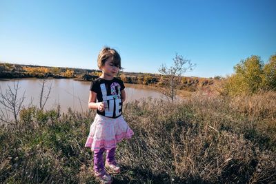 Full length of girl standing on footpath against clear blue sky