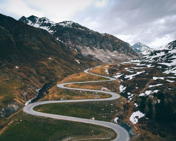 Scenic view of winding road by mountains during winter