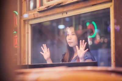 Young woman looking through window