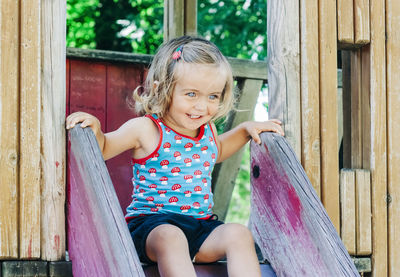 Smiling girl sitting on slide at playground