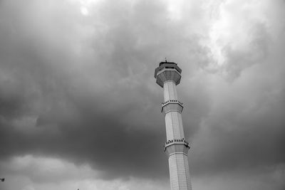 Low angle view of communications tower against cloudy sky