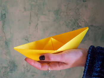 Cropped woman holding yellow paper boat