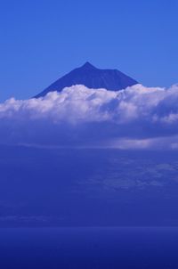 Scenic view of sea and mountains against blue sky