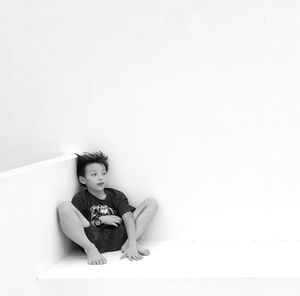 Boy sitting against white background