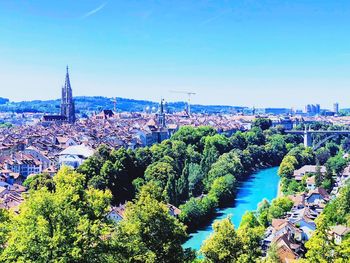 High angle view of river and buildings against blue sky