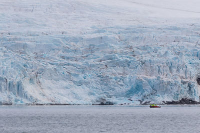 Unidentified tourists on a speedboat admiring large glacier from a close distance in svalbard