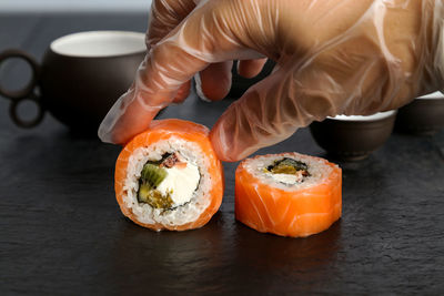 Cropped hand of vendor holding sushi on slate