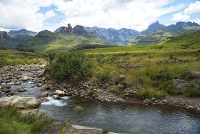 Scenic view of stream by mountains against sky