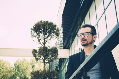 Portrait of young man looking at camera against sky