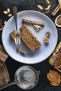 A sugar powdered slice of pumpkin sponge cake on a blue plate