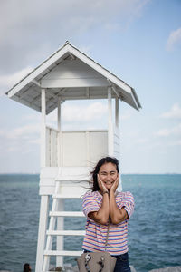 Portrait of smiling young woman standing against sea