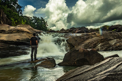 Full length of man standing on rock against sky