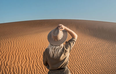 Rear view of woman standing on desert against sky