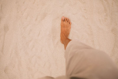 Low section of man standing on sand