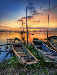 Boat moored on sea against sky during sunset