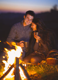 Young woman sitting on bonfire at night