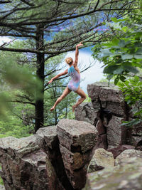 Woman sitting on rock against trees