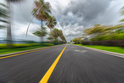 Road by trees against sky