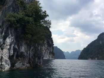 Scenic view of sea by mountains against sky