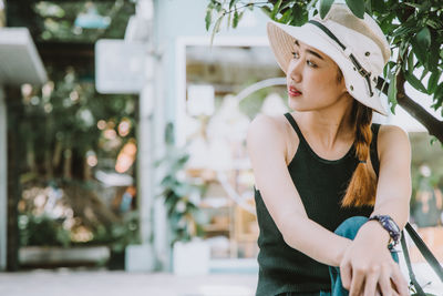Young woman looking away while standing outdoors