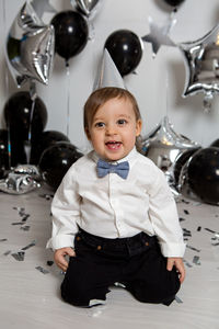 Boy in black clothes on his birthday party with balloon and silver stars