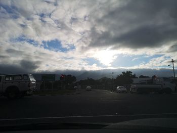 Vehicles on road against cloudy sky