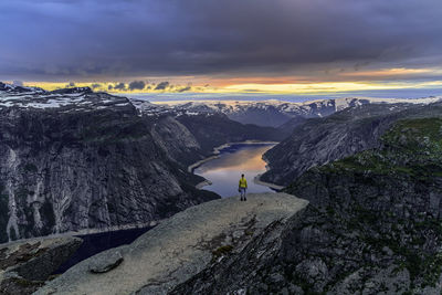 Man standing on mountain road against cloudy sky