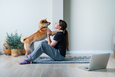 Doga concept. young woman in yoga position balancing with her dog. home online training with a pet