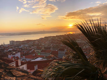 Aerial view of buildings by sea against sky during sunset