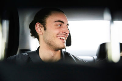 Close-up of happy young man riding in car