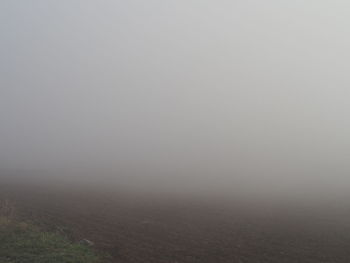 Scenic view of foggy field against sky