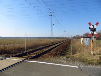 Railroad tracks by field against clear sky