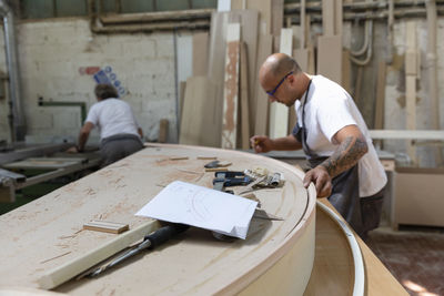 Furniture design paper on workbench with coworkers working in background at factory