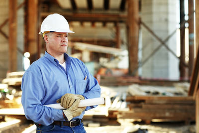 Male construction foreman holding plans looking off camera