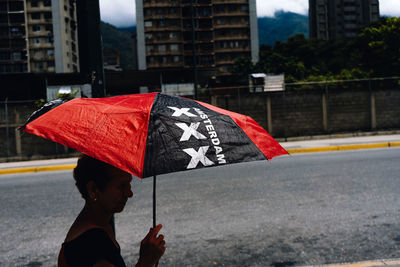 Man holding umbrella on street in rainy season