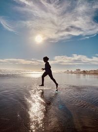 Full length of man at beach against sky during sunset