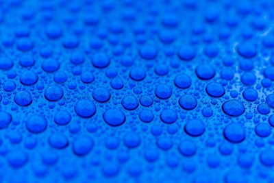 Close-up of water drops on the hood of a blue car after ceramic coating