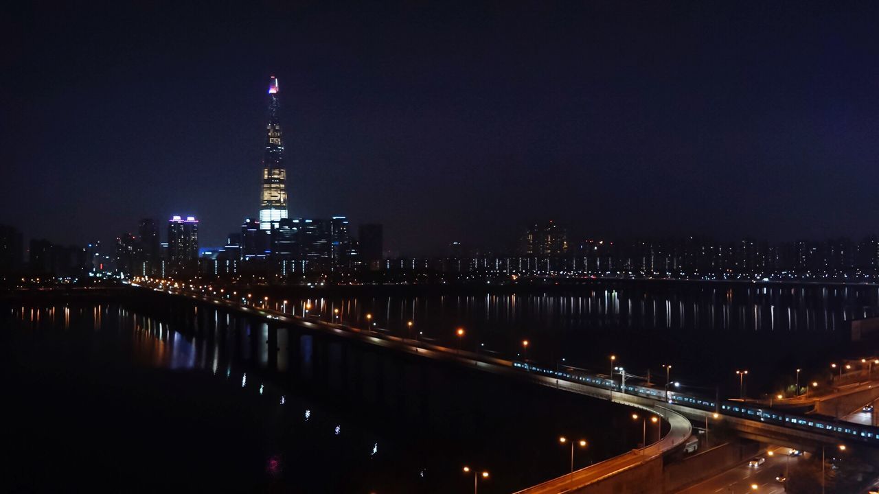 illuminated, night, built structure, architecture, tower, travel destinations, city, tourism, building exterior, skyscraper, sky, river, dark, modern, tall - high, tall, international landmark, engineering, urban skyline, city life, famous place, outdoors, capital cities, spire, development, no people, financial district