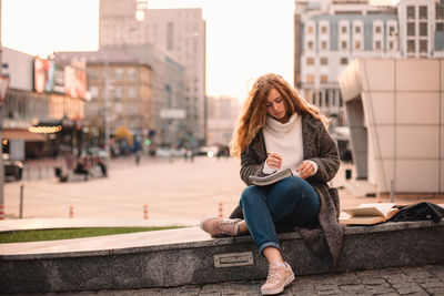 Full length of woman sitting in city