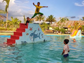 Boy jumping in swimming pool against sky