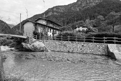 Bridge over river by buildings against sky