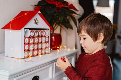 Child taking chocolate opening first gift in handmade advent calendar. sustainable christmas,.