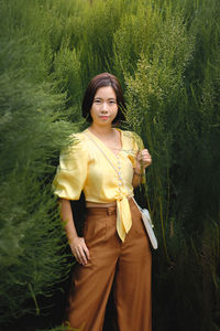 Young woman standing against plants