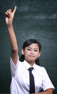 Portrait of girl in school uniform against blackboard