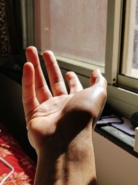 Close-up of woman hand on window at home