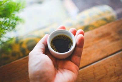 Cropped hand holding black coffee over table