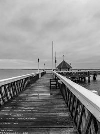 Pier on footbridge over sea against sky